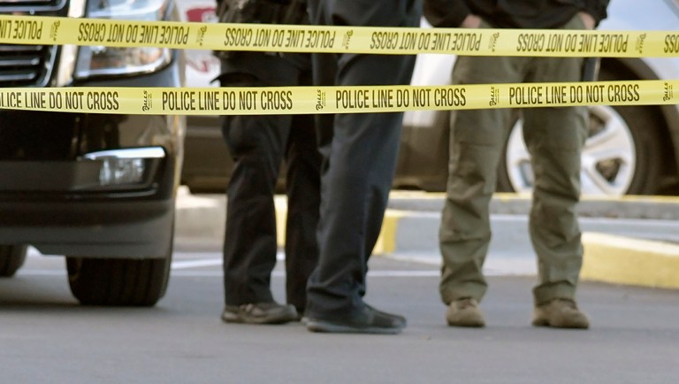 A gun lies on the ground inside a police barricade following a shooting at a Kroger grocery that left two people dead and a suspect in custody.