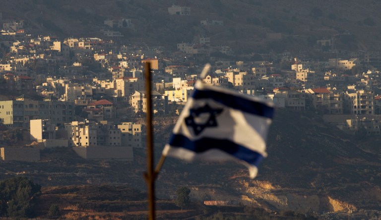 In this Thursday, Oct. 11, 2018, photo, an Israeli flag flutters in front of the village of Majdal Shams in the Israeli-controlled Golan Heights. Druze residents of the Israeli-controlled Golan Heights will for the first time join millions of Israelis voting in local elections next week. But candidates have had to keep a low profile amid a call by some Druze to boycott the polls, exposing a deep rift in the community over identity and the future of the occupied territory.