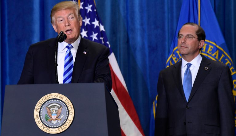 President Donald Trump, left, standing with Health and Human Services Secretary Alex Azar, right, talks about drug prices during a visit to the Department of Health and Human Services in Washington, Thursday, Oct. 25, 2018.