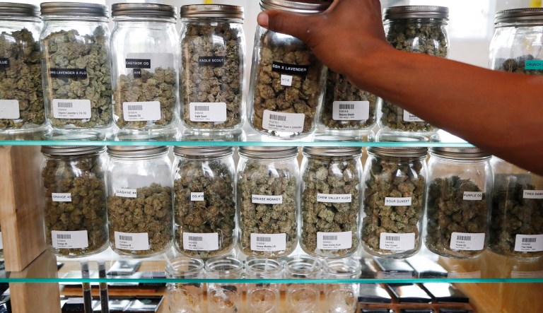 In this Tuesday, Oct. 2, 2018, file photo, a clerk reaches for a container of marijuana buds for a customer at Utopia Gardens, a medical marijuana dispensary, in Detroit.