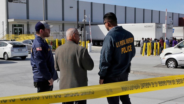 Postal inspectors confer outside of a postal facility in Burlingame, Calif.