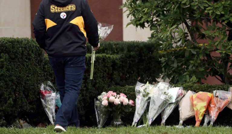 A person wearing a Pittsburgh Steelers jacket brings flowers to a makeshift memorial at the Tree of Life Synagogue in Pittsburgh, Sunday, Oct. 28, 2018. Robert Bowers, the suspect in Saturday's mass shooting at the synagogue, expressed hatred of Jews during the rampage and told officers afterward that Jews were committing genocide and he wanted them all to die, according to charging documents made public Sunday.