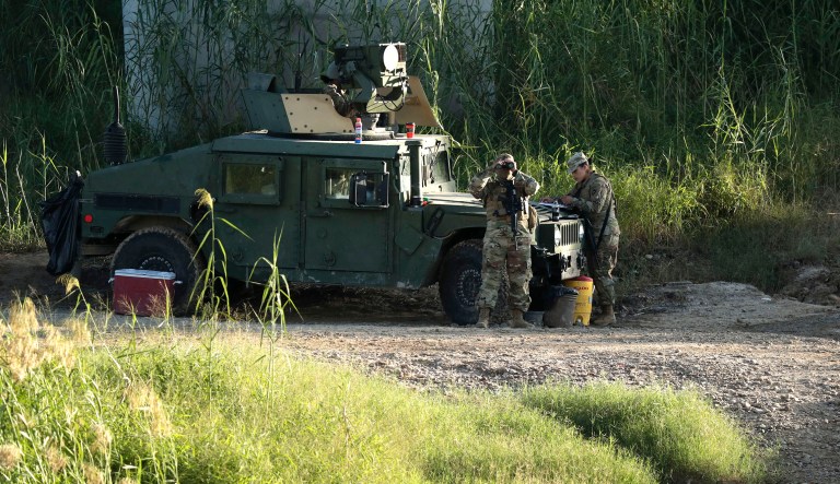 Members of the National Guard watch from the banks of the Rio Grande near the International Bridge in Roma, Texas. 