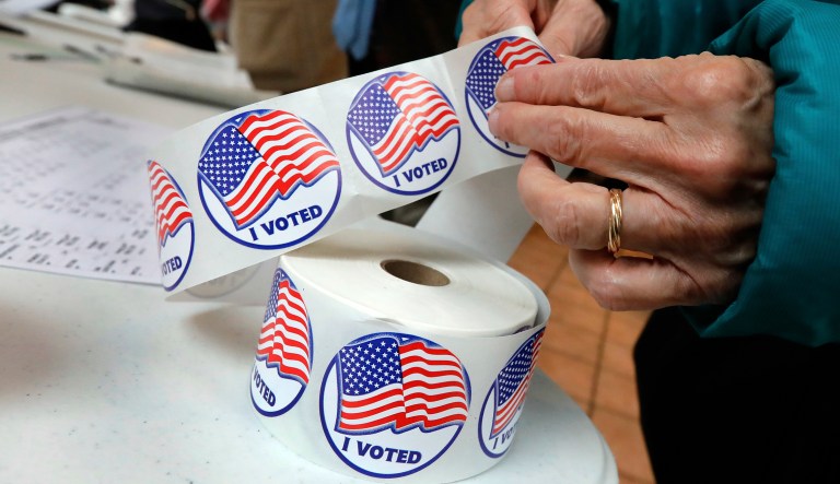 A voter retrieves her "I Voted" sticker after casting her ballot in N.Y.