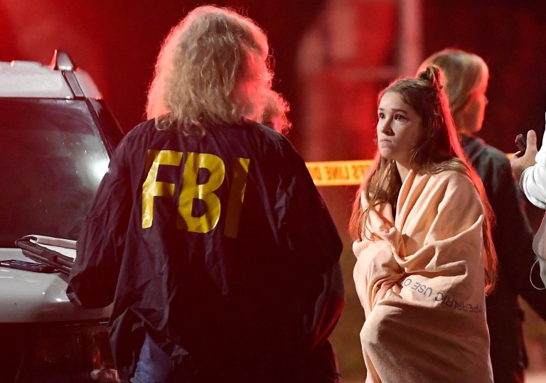 An FBI agent talks to a potential witness as they stand near the scene Thursday, Nov. 8, 2018, in Thousand Oaks, Calif. where a gunman opened fire Wednesday inside a country dance bar crowded with hundreds of people on "college night," wounding 11 people including a deputy who rushed to the scene. Ventura County sheriff's spokesman says gunman is dead inside the bar. 