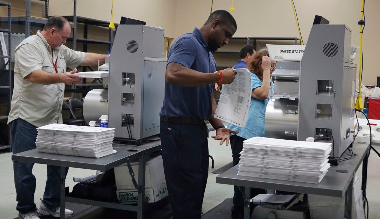 Election workers place ballots into electronic counting machines, Sunday, Nov. 11, 2018, at the Broward Supervisor of Elections office in Lauderhill, Fla. The Florida recount began Sunday morning in Broward County.