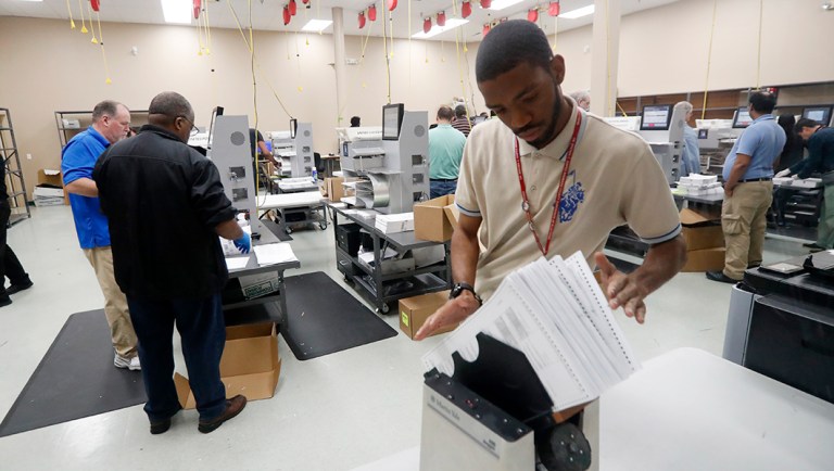 An employee at the Broward County Supervisor of Elections office prepares to sort ballots before being counted.