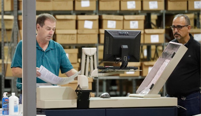 Employees run ballots through a machine before resuming a recount at the Palm Beach County Supervisor Of Elections office, Thursday, Nov. 15, 2018, in West Palm Beach, Fla.