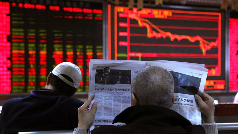 An investor reads the newspaper at a brokerage in Beijing, China.
