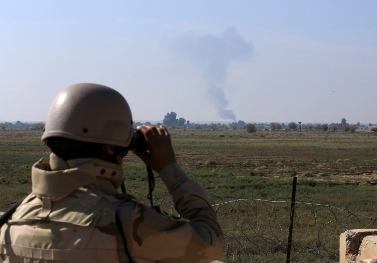 In this Tuesday, Nov. 13, 2018 photo, an Iraqi soldier watches smoke rising after an airstrike by US-led International coalition warplanes against ISIS, on the border between Syria and Iraq in Qaim, Anbar province, Iraq. More than a year after this Iraqi town was freed from the Islamic State group, booms from airstrikes still echo and columns of smoke are visible, rising beyond the earthen berms and concrete walls marking the border with Syria. On the other side, the fight is raging to capture one of the militant groupâs last enclaves.