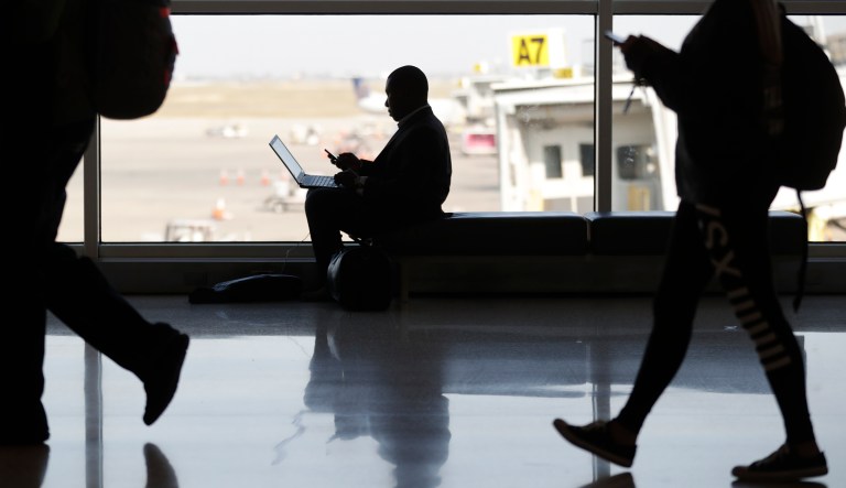 A traveler pauses to check his phone and computer as he waits for his flight at Indianapolis International Airport in Indianapolis, Wednesday, Nov. 21, 2018. The airline industry trade group Airlines for America expects that Wednesday will be the second busiest day of the holiday period behind only Sunday, when many travelers will be returning home after Thanksgiving.