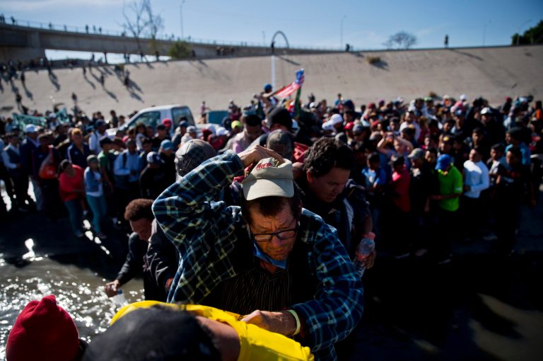 Migrants cross the river at the Mexico-U.S. border after pushing past a line of Mexican police at the Chaparral crossing in Tijuana, Mexico, Sunday, Nov. 25, 2018, as they try to reach the U.S. 