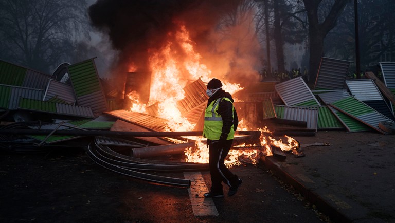 A demonstrator walks past a burning barricade near the Arc de Triomphe on the Champs-Elysees avenue during a demonstration.