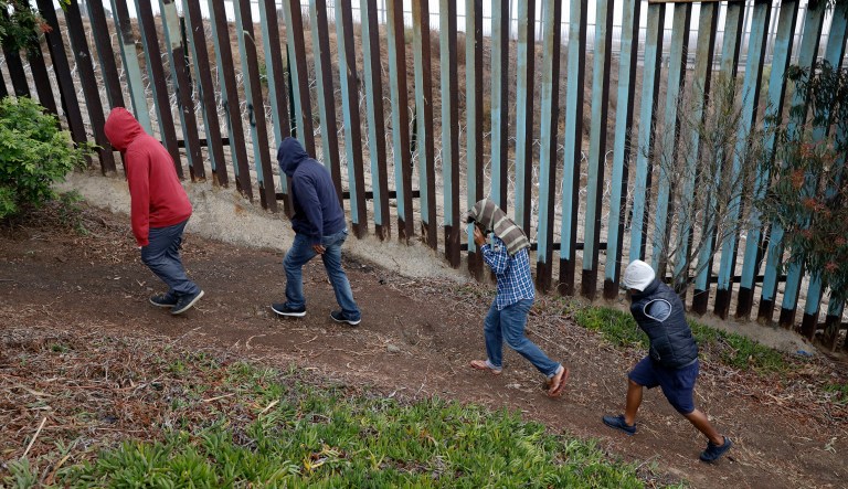 Central American migrants walk along the U.S. border fence looking for places they might be able to cross, in Playas de Tijuana, Mexico, Wednesday, Dec. 5, 2018. Discouraged by the long wait to apply for asylum through official ports of entry, many Central American migrants from recent caravans are choosing to cross the U.S. border wall and hand themselves in to border patrol agents. 