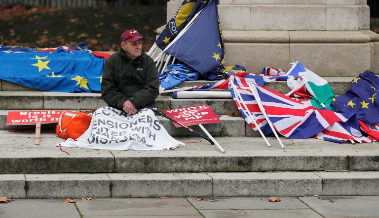 A protester rests outside the Houses of Parliament in London Thursday Dec. 6, 2018.  Britain's Prime Minister Theresa May's effort to win support for her Brexit agreement comes amid reports in British newspapers Thursday, predicting that Parliament could reject the deal by more than 100 votes.