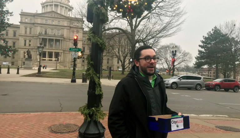 Lansing City Pulse reporter Kyle Kaminski stands outside Lansing City Hall, across the street from the Capitol and hands out free joints, Thursday, Dec. 6, 2018, in Lansing, Mich. The alternative weekly newspaper did so to mark the official legalization of recreational marijuana in Michigan. 