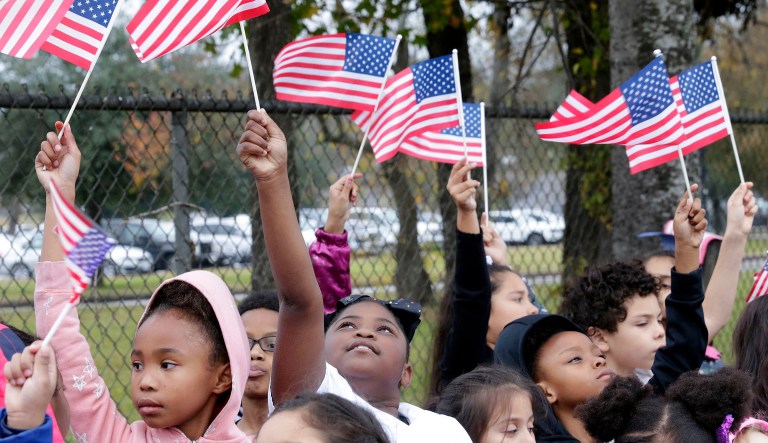 Students from Salyer Elementary School wave flags as the train carrying the body of former president George H.W. Bush travels past their school on the way to Bush's final internment Thursday, Dec. 6, 2018, in Spring, Texas.