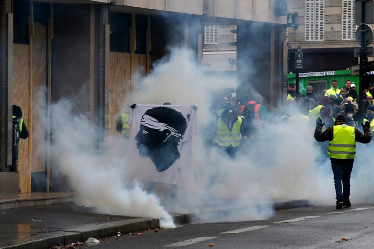 A protester holds the flag of the Corsica island near the Champs-Elysees avenue Saturday, Dec. 8, 2018 in Paris. Crowds of yellow-vested protesters angry at President Emmanuel Macron and France's high taxes tried to converge on the presidential palace Saturday, some scuffling with police firing tear gas, amid exceptional security measures aimed at preventing a repeat of last week's rioting.