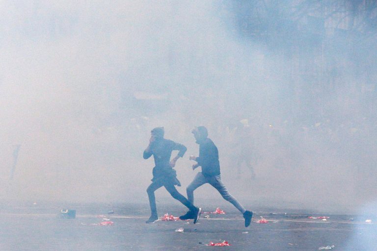 Demonstrators run away from tear gas fired by riot police during clashes in Paris, France, Saturday, Dec. 8, 2018. Crowds of protesters angry at President Emmanuel Macron and France's high taxes tried to converge on the presidential palace Saturday, some scuffling with police firing tear gas, amid exceptional security measures aimed at preventing a repeat of last week's rioting. 