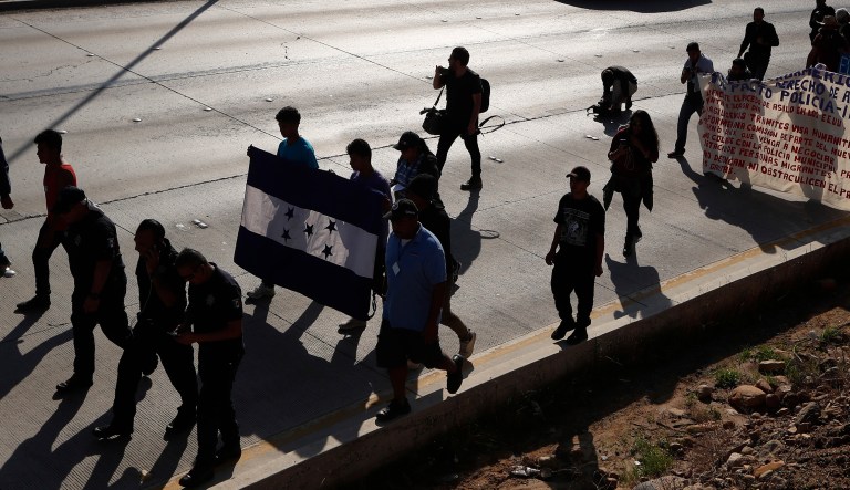 Honduran migrants march with their nation's flag to the U.S. consulate in Tijuana, Mexico, Tuesday, Dec. 11, 2018. Migrants want U.S. authorities to speed up the asylum application process for members of migrant caravans seeking to enter the U.S., including accepting more applications per day.