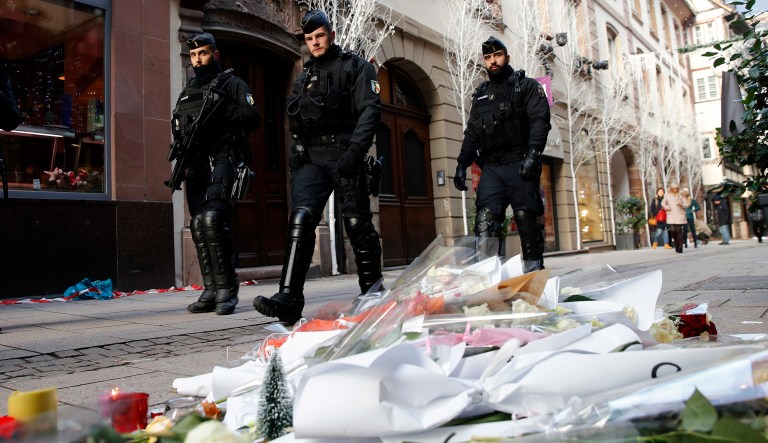French police officers patrol in the streets front of flowers to pay respects of the victims following an attack killing three persons and wounding at least 13, in Strasbourg, eastern France, Thursday, Dec. 13, 2018. Police union officials identified the suspected assailant as Frenchman Cherif Chekatt, a 29-year-old with a thick police record for crimes including armed robbery and monitored as a suspected religious radical by the French intelligence services. 