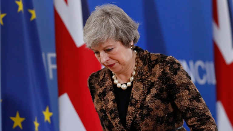 British Prime Minister Theresa May walks by the Union Flag and EU flag as she departs a media conference at an EU summit in Brussels.