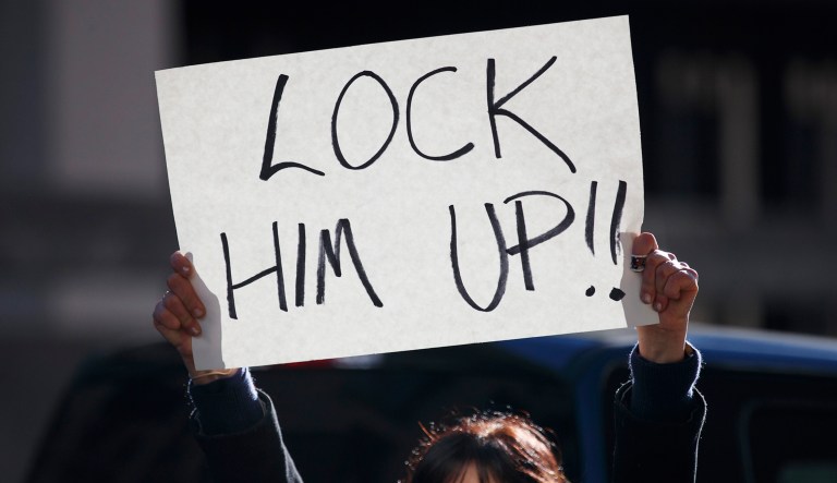 A woman holds a sign that reads "Lock Him Up!!" outside federal court in D.C.