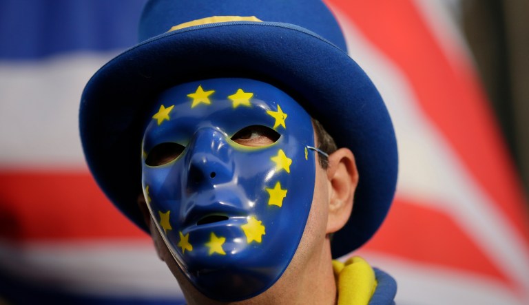 An anti-Brexit demonstrator wears a mask bearing the stars of the European flag during a protest outside the houses of Parliament, in London, Wednesday Dec. 19, 2018.