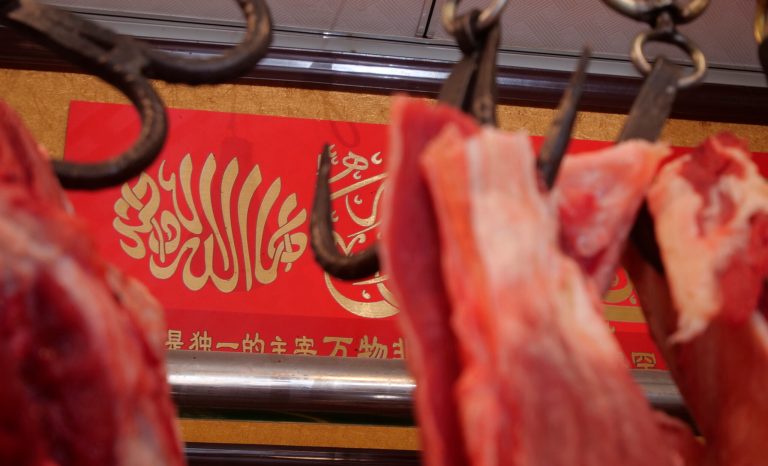 In this Dec. 7, 2018, photo, an Arabic inscription reading "there is no god but God" is hung in a butcher shop in the Islamic neighborhood of Niujie in Beijing, China. 