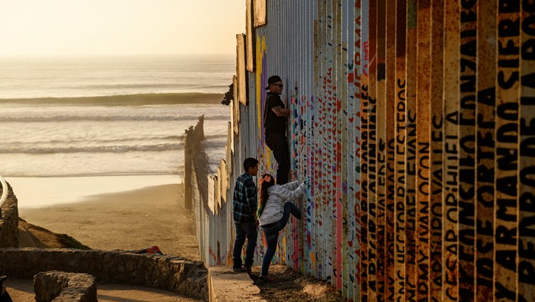 A man climbs up a section of a U.S.-Mexico border wall in Tijuana, Mexico.