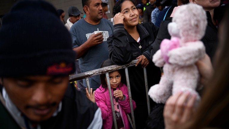 A girl from Honduras waits for a present given by a nongovernmental organization outside an empty warehouse used as a shelter set up for migrants in downtown Tijuana, Mexico.