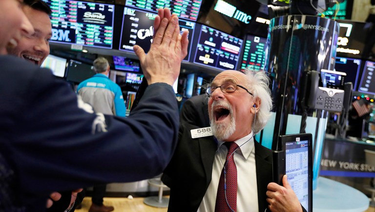 Traders Peter Tuchman, right, slaps a high five before the closing bell on the floor of the New York Stock Exchange, Wednesday.