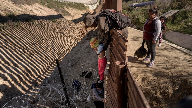 A man passes a Mexican migrant baby to her mother after they jump the border fence to get into the U.S. side to San Diego, Calif., from Tijuana, Mexico.