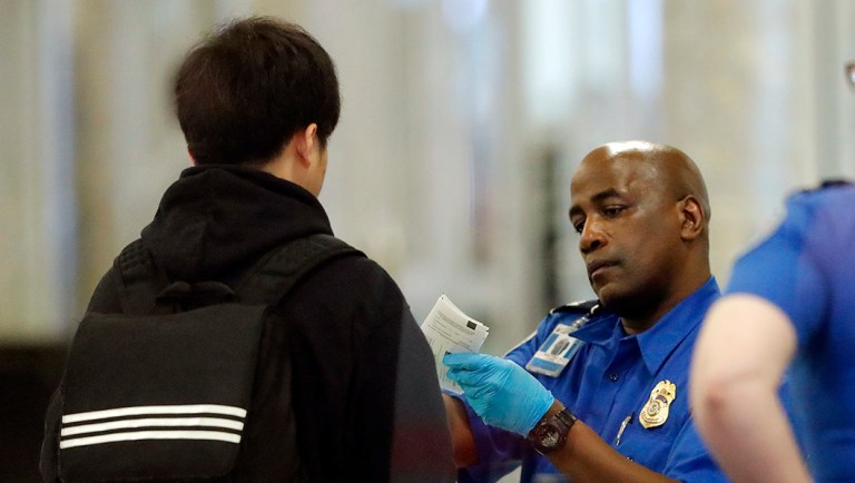 A Transportation Security Administration employee checks an air traveler's identification.