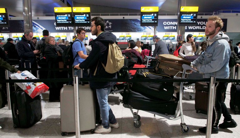 Passengers wait in a queue in departures at Heathrow Airport in London.