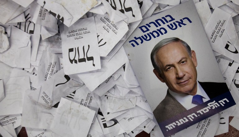 In this Wednesday, March 18, 2015, file photo, an election campaign poster with the image of Israeli Prime Minister Benjamin Netanyahu lies among ballot papers at his party's election headquarters in Tel Aviv.