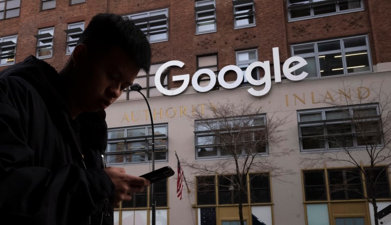 A man using a mobile phone walks past Google offices in New York.