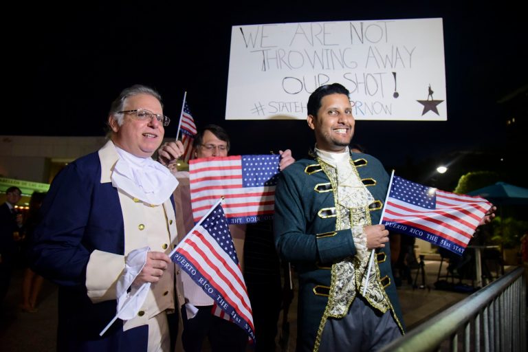Dan Santiago, right, and Miguel Gallo, left, hold a demonstration in favor of statehood at the entrance plaza of the Santurce Fine Arts Center moments before the premiere of the award-winning Broadway musical, Hamilton, starring its creator, New York native of Puerto Rican descent Lin-Manuel Miranda, in San Juan, Puerto Rico, Friday Jan. 11, 2019. Several Democratic members plan to see the show Sunday.
