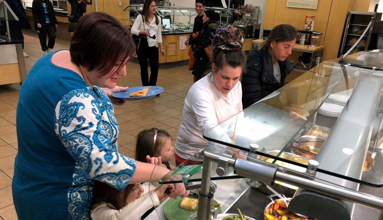 U.S. Coast Guard spouse Mariah Battermann, left, fills her plate at a college offering a free dinner for active-duty Coast Guard members and their families in Rhode Island and southeastern Massachusetts who are working without pay during the partial federal shutdown. 