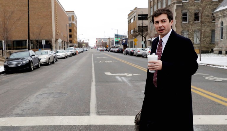 Mayor Pete Buttigieg talks with a reporter as he walks in downtown South Bend, Ind.