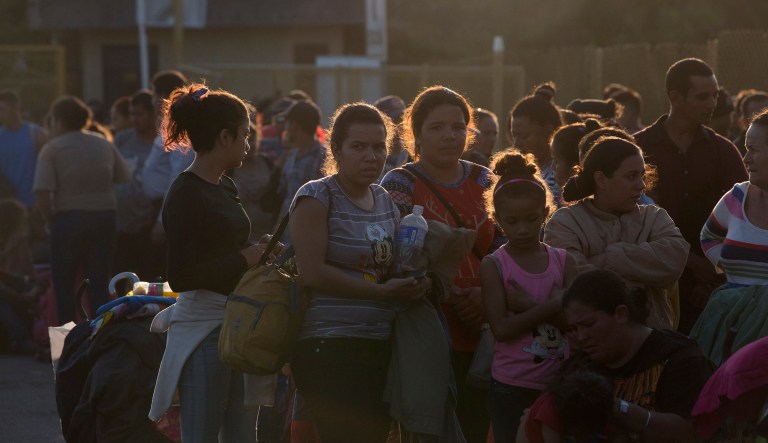 Migrants from Honduras and El Salvador stand in line waiting to enter bridge over the Suchiate River on the border between Guatemala and Mexico, in Tecun Uman, Guatemala, early Saturday, Jan. 19, 2019.