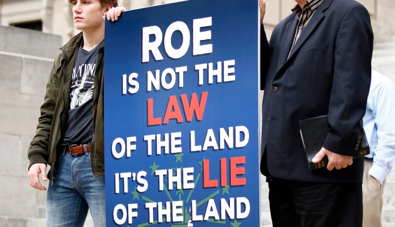 Anti-abortion activists hold a sign condemning Roe v. Wade, a U.S. Supreme Court decision in 1973 that recognized a woman's constitutional right to an abortion, at the Capitol in Jackson, Miss., Tuesday, Jan. 22, 2019. 