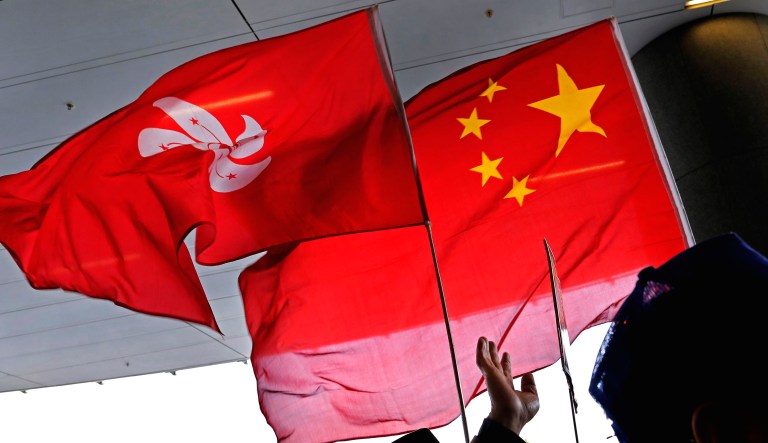 Pro-Beijing protesters raise the Chinese National flag and the Hong Kong flag during a gathering outside the legislative building in Hong Kong.