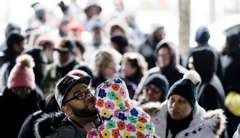 Anthony Spencer, whose wife, Chastity, right, is a furloughed federal worker, holds his daughter, Sydney, as they wait in line with others who are affected by the partial government shutdown for Philabundance volunteers to distribute food under Interstate 95 in Philadelphia.