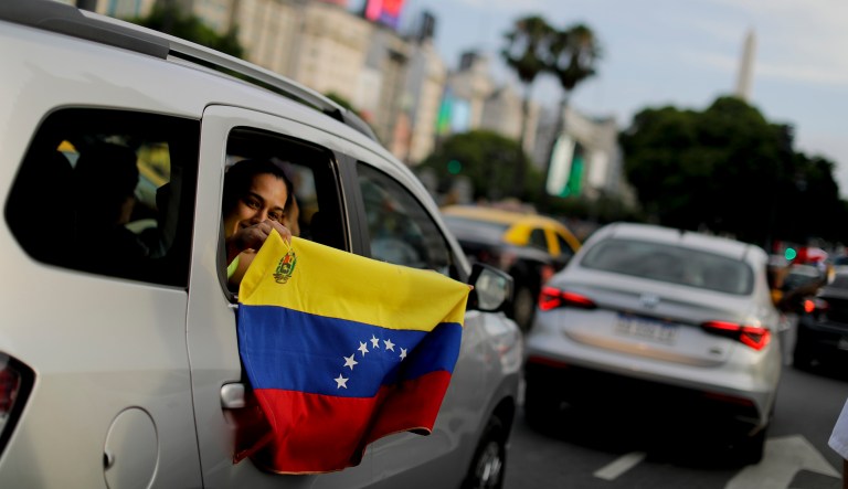 A Venezuelan anti-government protester holds a Venezuelan flag from the window of a car during a demonstration in Buenos Aires, Argentina, Wednesday, Jan. 23, 2019. Hundreds of people, mostly Venezuelan migrants, held a rally against Venezuelan President Nicolas Maduro and in favor of Juan Guaido, head of Venezuela's opposition-run congress who today proclaimed himself president of the South American nation.