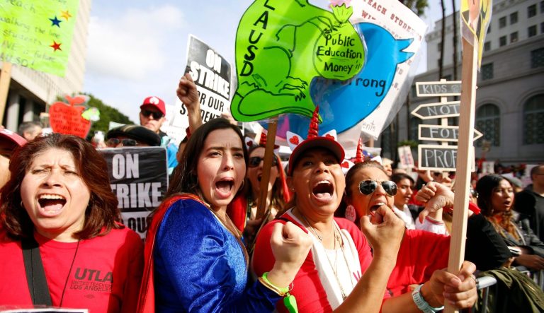 In this Friday, Jan. 18, 2019 file photo, elementary school teachers Iris Marin, center, and Mireya Gutierrez, right, and Lorena Redford, clench fists at a rally in downtown Los Angeles.
