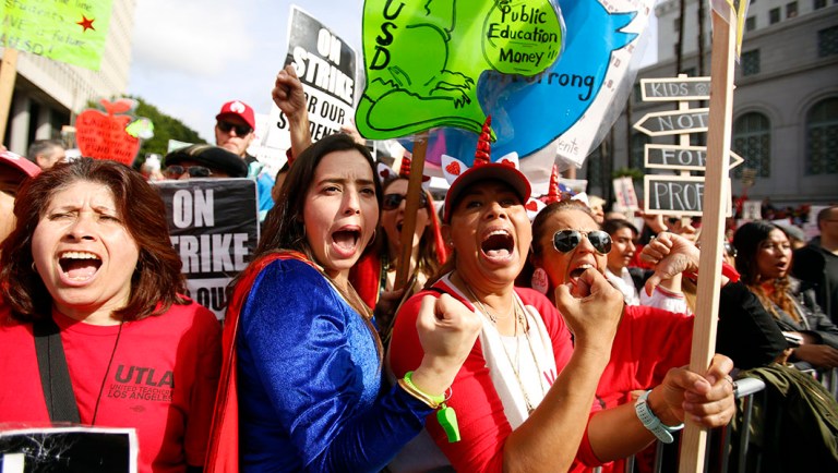 Elementary school teachers Iris Marin, center, and Mireya Gutierrez, right, and Lorena Redford, clench fists at a rally in downtown Los Angeles.
