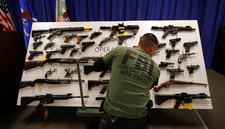 An FBI agent displays seized firearms before a news conference Wednesday, Feb. 13, 2019, in Los Angeles. 