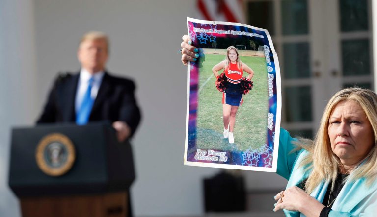 President Donald Trump, left, looks over to Susan Stevens, right, who is holding up a picture of her daughter, during an event in the Rose Garden at the White House Friday, Feb. 15, 2019 in Washington. Stevens lost her daughter to opioids. 