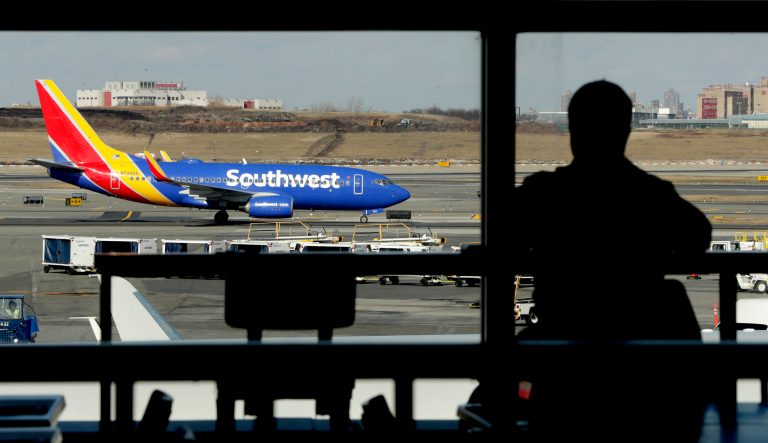 In this Jan. 25, 2019 photo a Southwest Airlines jet moves on the runway as a person eats at a terminal restaurant at LaGuardia Airport in New York. 